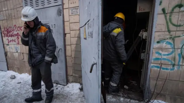 Two electricians stand on the phone in the snow