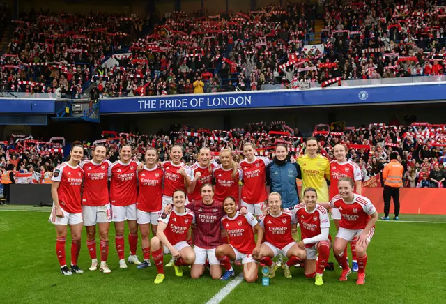 Arsenal players pose for a team photo in front of the Stamford Bridge away end