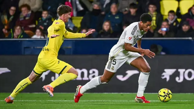 Real Madrid's English midfielder #05 Jude Bellingham (R) runs with the ball chased by Villarreal's Spanish defender #26 Pau Navarro during the Spanish league football match between Villarreal CF and Real Madrid.