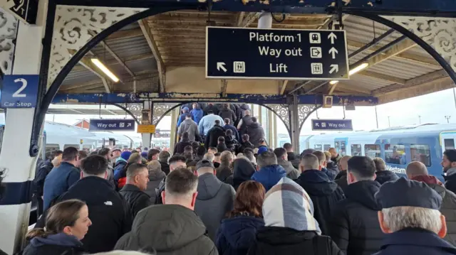 A large crowd of people leaving a train station.