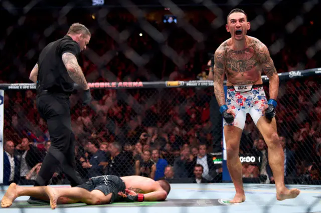 Justin Gaethje laying face down with Max Holloway celebrating
