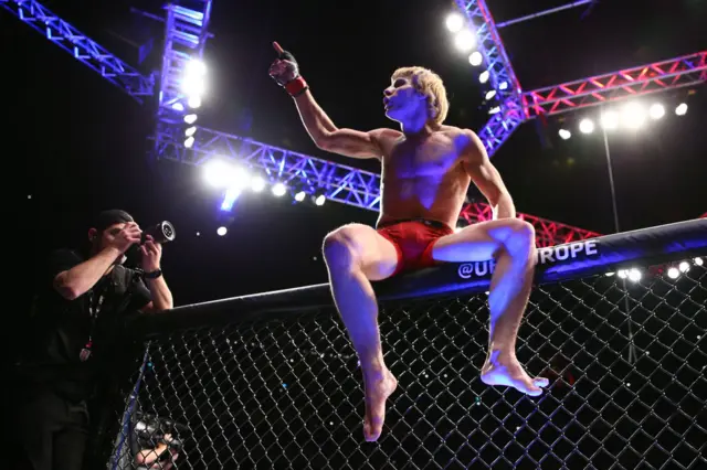 Paddy Pimblett on top fo the cage celebrating