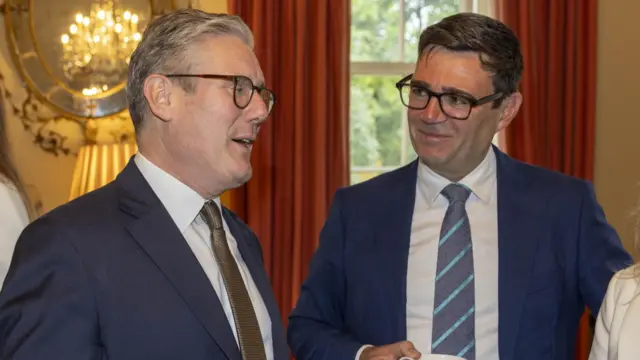 Starmer speaking while Burnham looks on, smiling