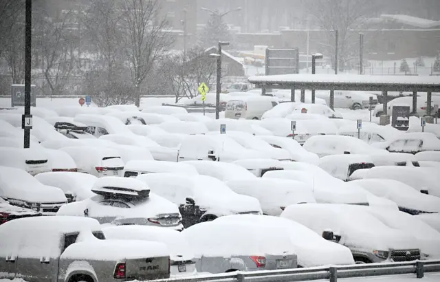 Snow collects on parked cars at Albany International Airport