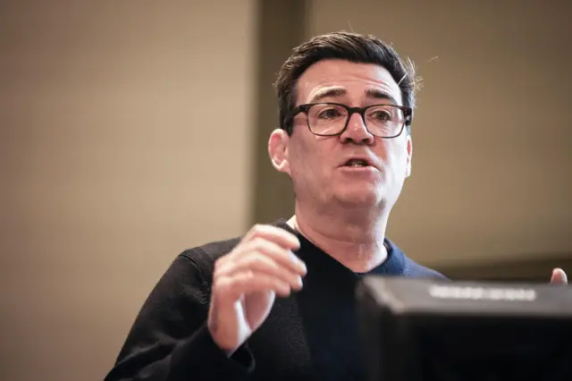 Andy Burnham speaking at a podium