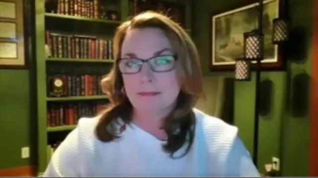 Woman wearing a white jumper and glasses