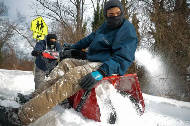 A man sits on a red snow blower
