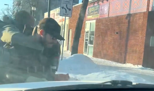 A man in a cap is seen through the windscreen of a car