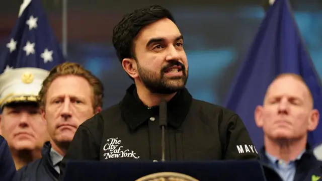 Zohran Mamdani stands at a podium as officials stand behind him on Sunday