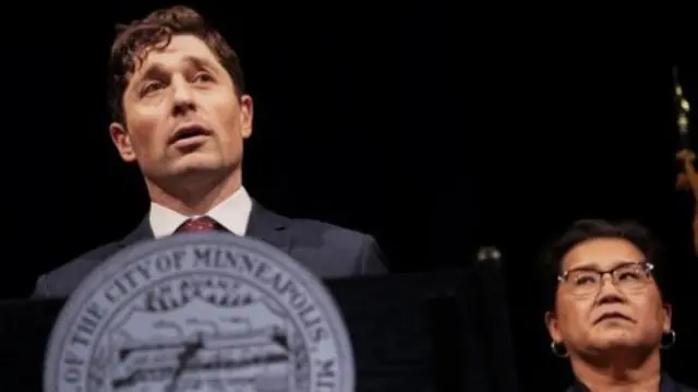 Mayor of Minneapolis Jacob Frey stands behind the city's official seal