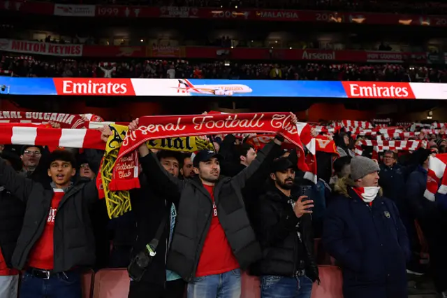 Fans of Arsenal show their support as they hold scarves