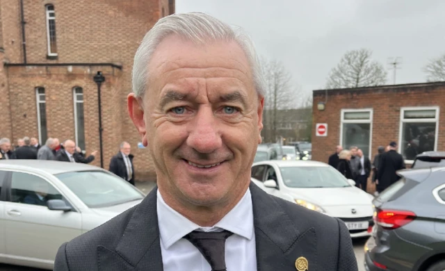 Ian Rush smiling outside the church wearing a grey and white suit.