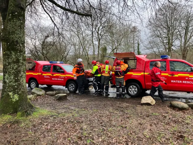 People in high visility clothing next to water rescue cars.