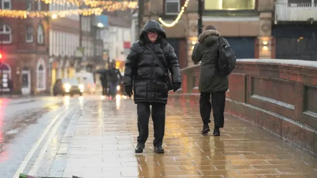 A man walking in the rain wearing a raincoat