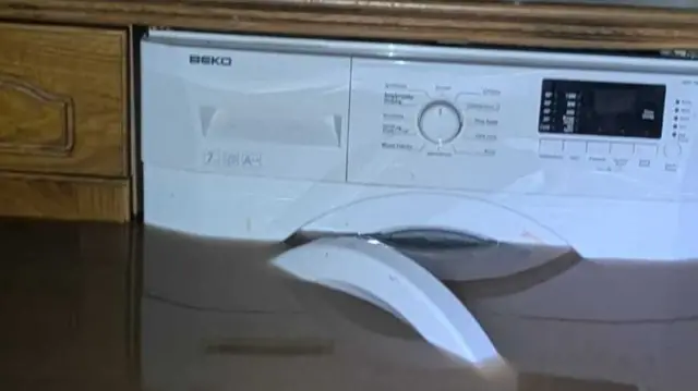 Flooding in a kitchen. The water is as high as the washing machine pictured