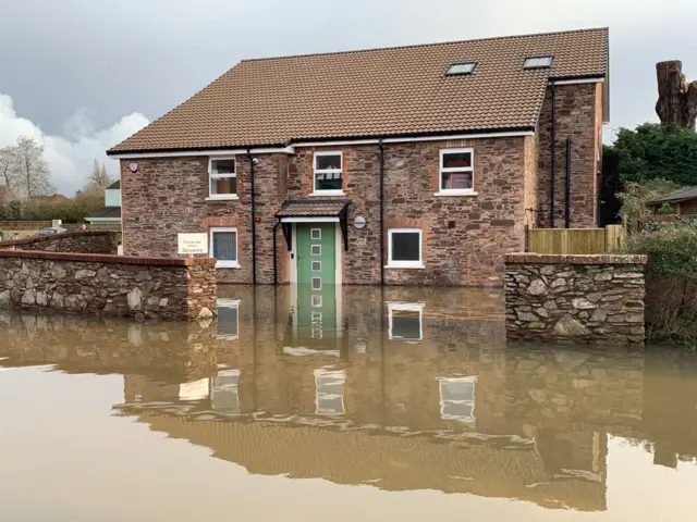 Muddy floodwater high against a house in Taunton. The level is higher than the bottom of the green door but has not reached the downstairs windowds