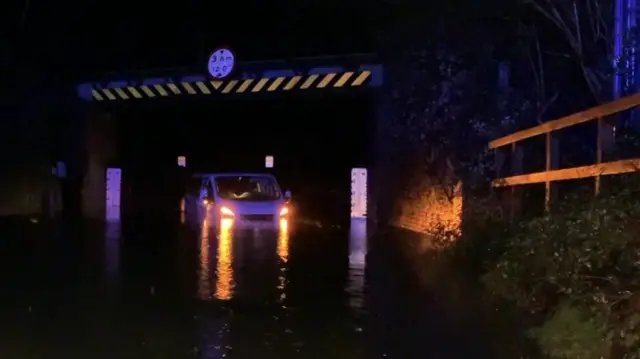 Van stuck in flood water under bridge