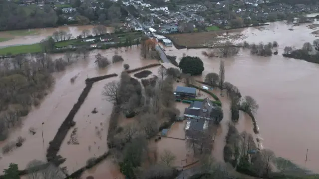 A large field that has been flooded with houses in the middle.