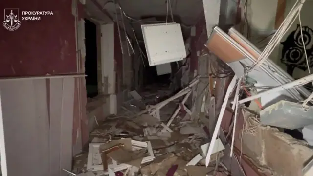 Screengrab from a video shows inside of a school building heavily damaged, with walls and objects scattered across the corridor