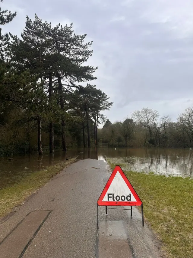 Southampton Common's green space under water. A flood sign is put on the path.
