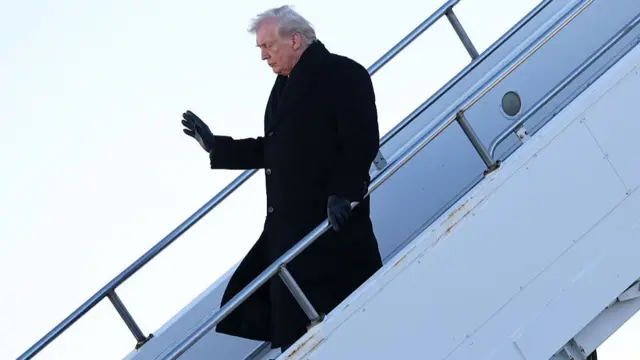 Trump walks down the steps of Air Force One. He wears a black jacket and black gloves