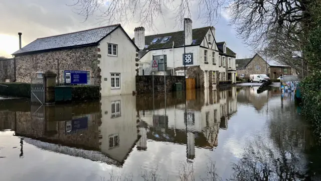 Flooded street with houses, reflection of houses can be seen in the floodwater