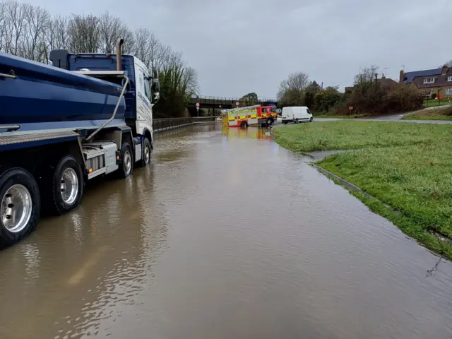 Fire crews at Stratton where a closure is causing long delays. The road is completely under water.