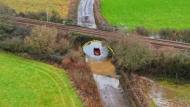 Car trapped in flood water under rail bridge