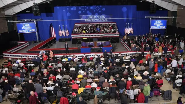 above shot of people sitting in chairs in front of stage adorned with American flags