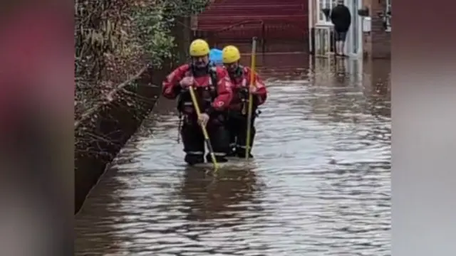 Fire crews wading through flood water