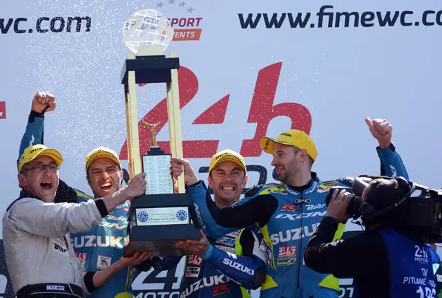 The Suzuki Endurance racing team manager France's Dominique Meliand, France's Etienne Masson, France's Vincent Philippe and France's Anthony Delhalle, (Suzuki GSXR Formula EWC N°30) celebrate on the podium with their trophies after winning the 38th edition of the Le Mans 24 hours moto endurance race on April 19, 2015 in Le Mans, western France.