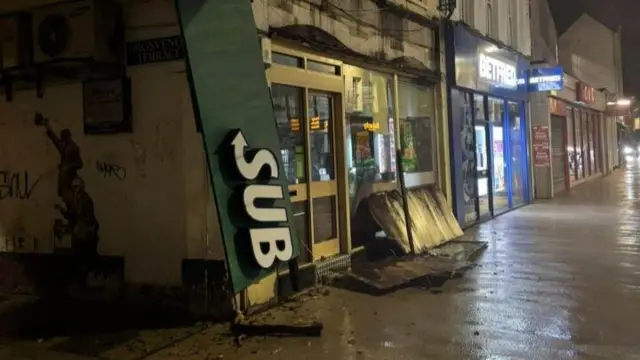 A dark street in Cheltenham which has been battered by the winds. Hoarding and signs have fallen down