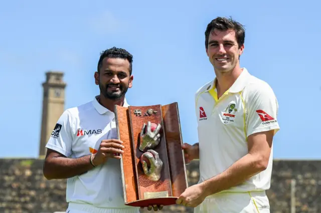 Sri Lanka's captain Dimuth Karunaratne (L) and his Australian counterpart Pat Cummins pose with the Warne-Muralitharan Test trophy