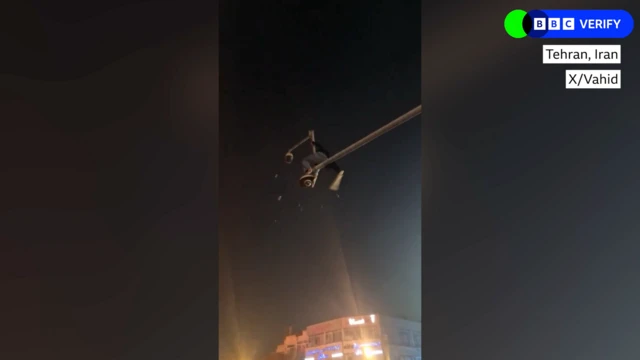 A man on top of a post hitting a surveillance camera