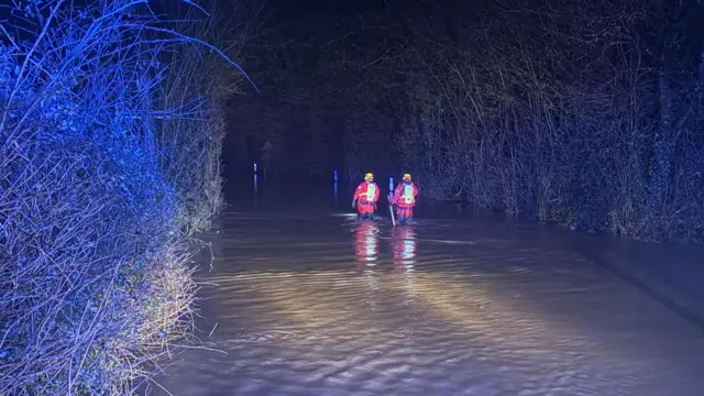 Two firefighters walk through flood water