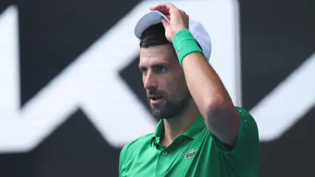 Novak Djokovic adjusts his cap