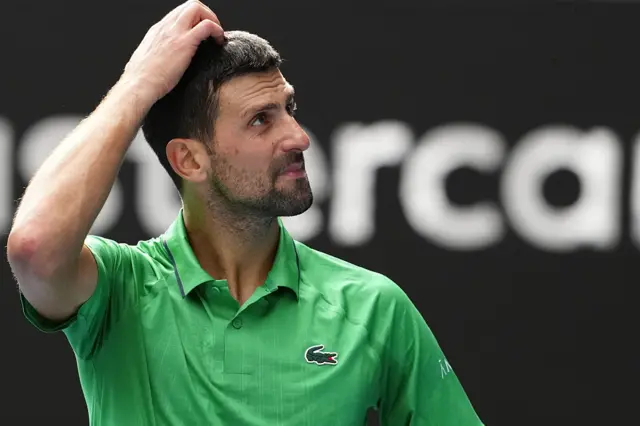 Novak Djokovic scratches his head