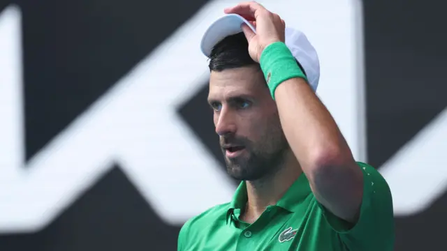 Novak Djokovic adjusts his cap