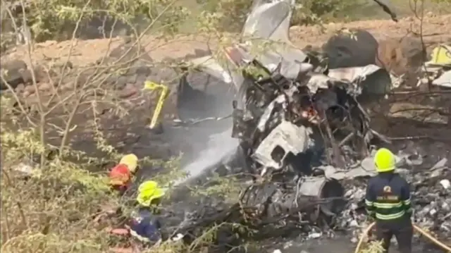 Three firefighters douse flames of the crashed aircraft
