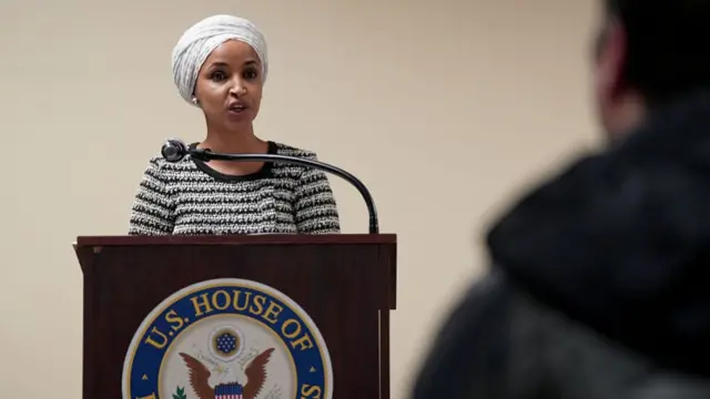 Omar standing at a podium and speaking into a microphone