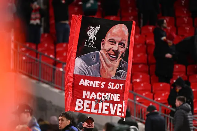 Fans of Liverpool show their support as they hold a banner depicting the image of Arne Slot
