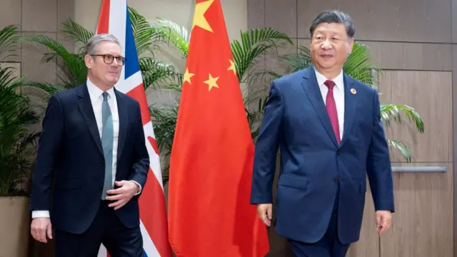 Keir Starmer walks next to Xi Jinping. A Chinese flag and the Union Flag can be seen behind them.