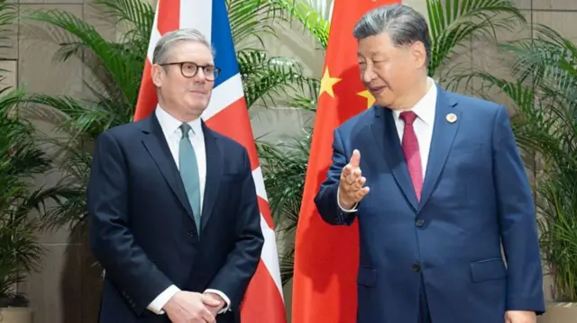 British Prime Minister Sir Keir Starmer and Chinese leader Xi Jinping talking to each other while standing in front of their respective flags