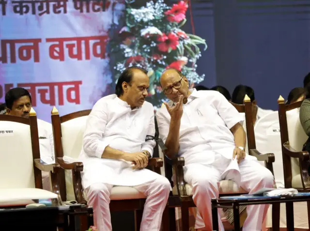 Ajit Pawar (left) with his uncle Sharad Pawar. Both leans towards each other as they sit on white cushioned chairs wearing white kurtas