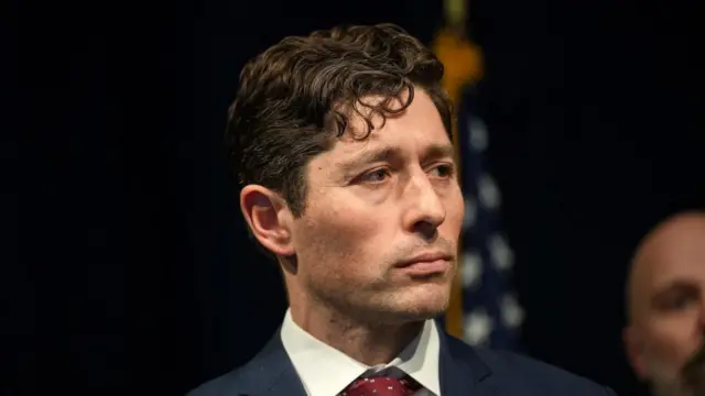 A file photo of Minneapolis Mayor Jacob Frey, he is wearing and suit and standing in front of a US flag