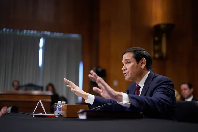 Marco Rubio in Senate with hand raised, image shows his profile.