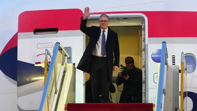 Keir Starmer waving as he steps out of an aeroplane