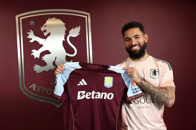 Douglas Luiz holding an Aston Villa shirt