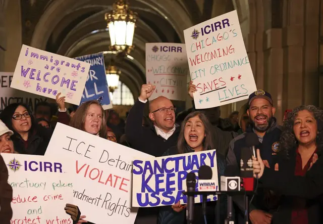People hold pro-immigrant placards at Chicago City Hall on 13 January