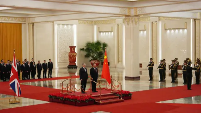 Starmer and Qiang stand on a platform on a red carpet